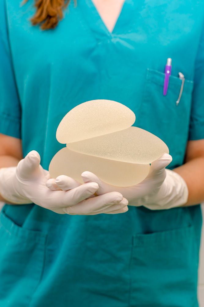 Photo of gloved hands holding multiple breast implants